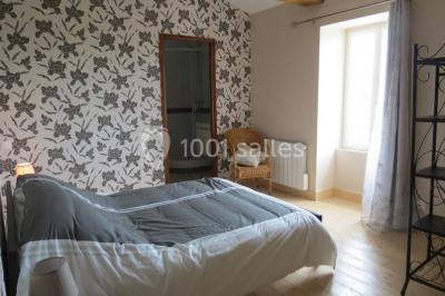 Chambre avec lits superposés en bois, parquet, papier peint floral, accès à une salle de bain et vue sur un jardin.