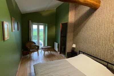 Chambre avec lits superposés en bois, parquet, papier peint floral, accès à une salle de bain et vue sur un jardin.