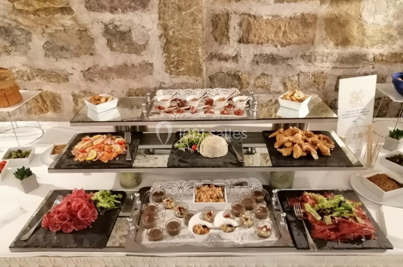 Buffet composé de plats variés tels que charcuteries, salades, desserts et amuse-bouches, présenté sur des plateaux.