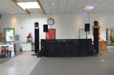 Salle de réception avec une piste de danse, une table dressée à gauche et un équipement de sonorisation au centre.