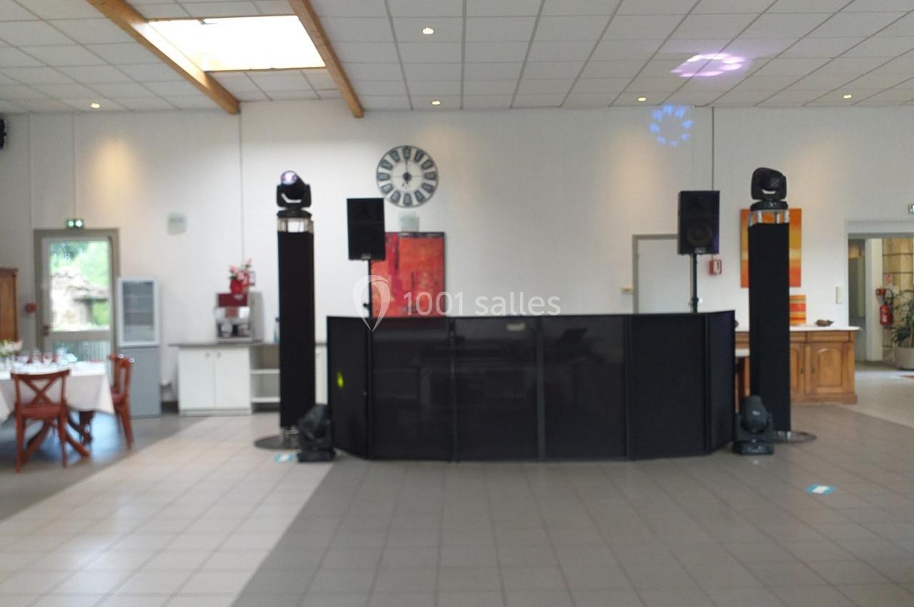 Salle de réception avec une piste de danse, une table dressée à gauche et un équipement de sonorisation au centre.