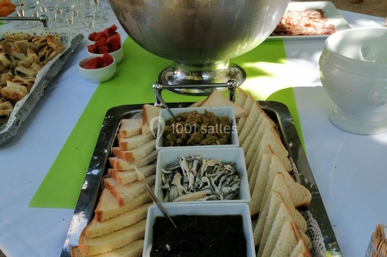 Plateau avec des tranches de pain, tapenades et anchois, présenté sur une table avec d'autres amuse-bouches.