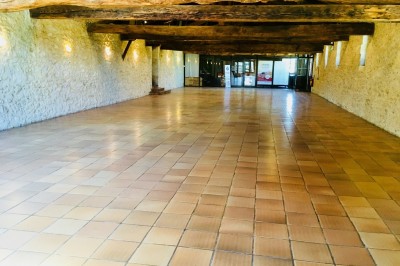 Miniature Location salle Podensac (Gironde) - Maison des Vins de Graves #7 Salle spacieuse avec sol en carrelage, mezzanine en bois, murs en pierre et porte vitrée ouverte.