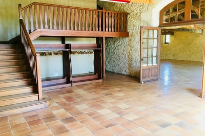 Miniature Location salle Podensac (Gironde) - Maison des Vins de Graves #9 Salle spacieuse avec sol en carrelage, mezzanine en bois, murs en pierre et porte vitrée ouverte.