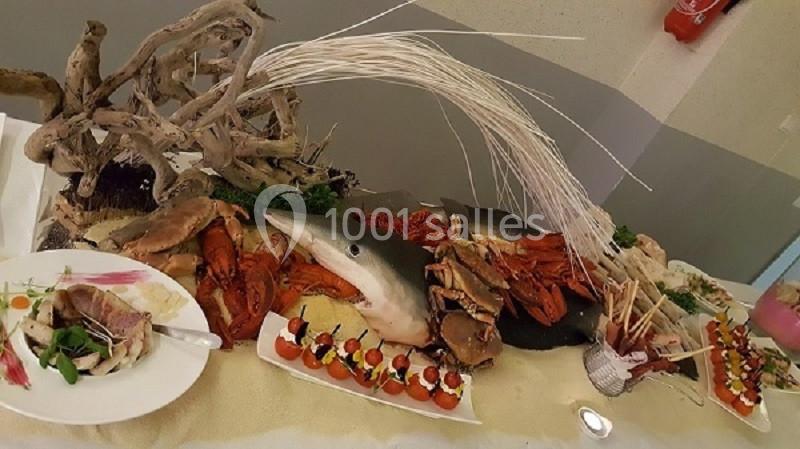 Plateau de fruits de mer et poissons décoré avec des crustacés, un requin et des éléments végétaux sur une table.