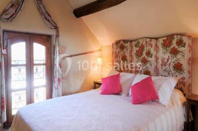 Façade d'une maison en briques et bois avec fenêtres à volets, entourée de végétation et baignée de lumière naturelle.