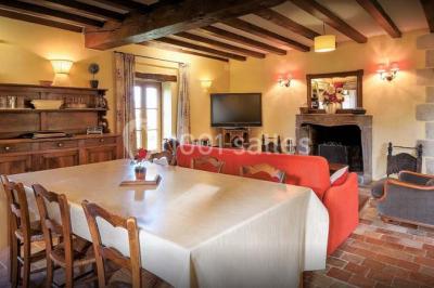 Façade d'une maison en briques et bois avec fenêtres à volets, entourée de végétation et baignée de lumière naturelle.