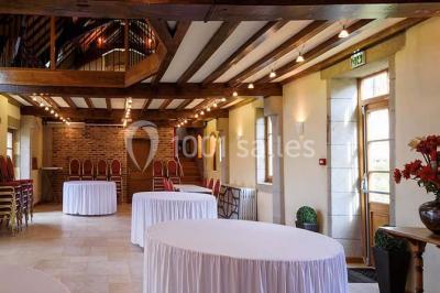 Façade d'une maison en briques et bois avec fenêtres à volets, entourée de végétation et baignée de lumière naturelle.