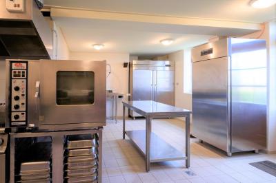 Façade d'une maison en briques et bois avec fenêtres à volets, entourée de végétation et baignée de lumière naturelle.