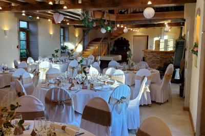 Façade d'une maison en briques et bois avec fenêtres à volets, entourée de végétation et baignée de lumière naturelle.