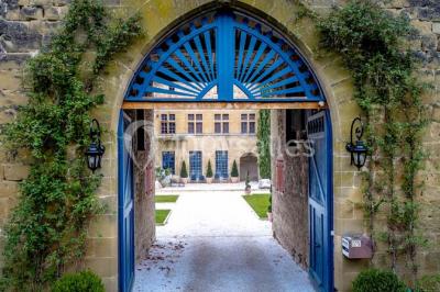 Allée éclairée par des lampes au sol, bordée d'arbres et menant à une entrée illuminée dans l'obscurité.