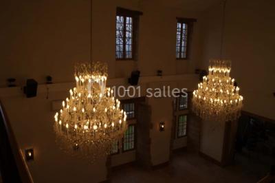 Allée éclairée par des lampes au sol, bordée d'arbres et menant à une entrée illuminée dans l'obscurité.