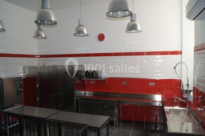 Allée éclairée par des lampes au sol, bordée d'arbres et menant à une entrée illuminée dans l'obscurité.