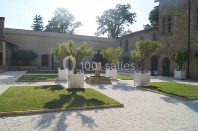 Allée éclairée par des lampes au sol, bordée d'arbres et menant à une entrée illuminée dans l'obscurité.