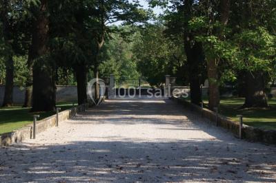 Allée éclairée par des lampes au sol, bordée d'arbres et menant à une entrée illuminée dans l'obscurité.