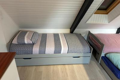 Chambre moderne avec mur vert, lit double décoré de coussins, luminaires muraux et tapis clair au sol.