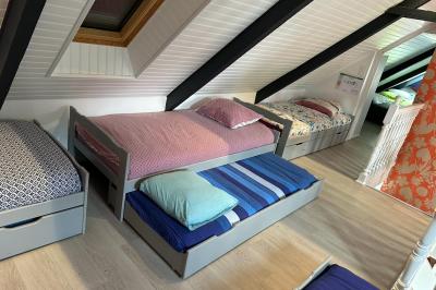 Chambre moderne avec mur vert, lit double décoré de coussins, luminaires muraux et tapis clair au sol.