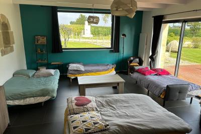 Chambre moderne avec mur vert, lit double décoré de coussins, luminaires muraux et tapis clair au sol.