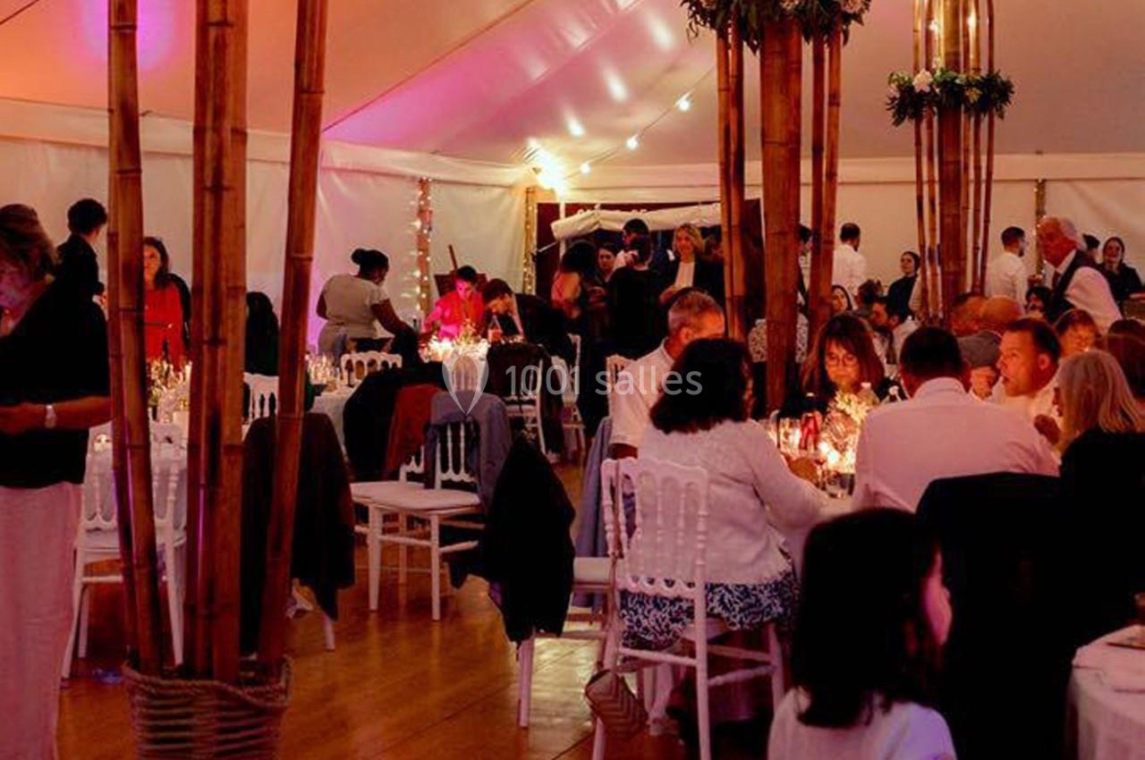 Des invités dînent dans une tente éclairée, décorée de bambous et de lumières tamisées.