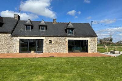 Chambre moderne avec mur vert, lit double décoré de coussins, luminaires muraux et tapis clair au sol.