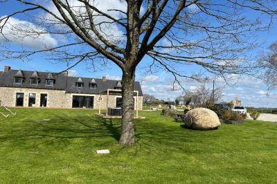 Chambre moderne avec mur vert, lit double décoré de coussins, luminaires muraux et tapis clair au sol.
