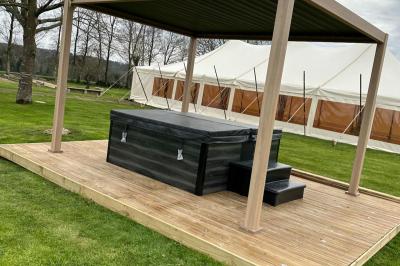 Chambre moderne avec mur vert, lit double décoré de coussins, luminaires muraux et tapis clair au sol.