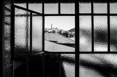 Des personnes se détendent dans une piscine extérieure avec vue sur un village et un clocher sous un ciel dégagé.