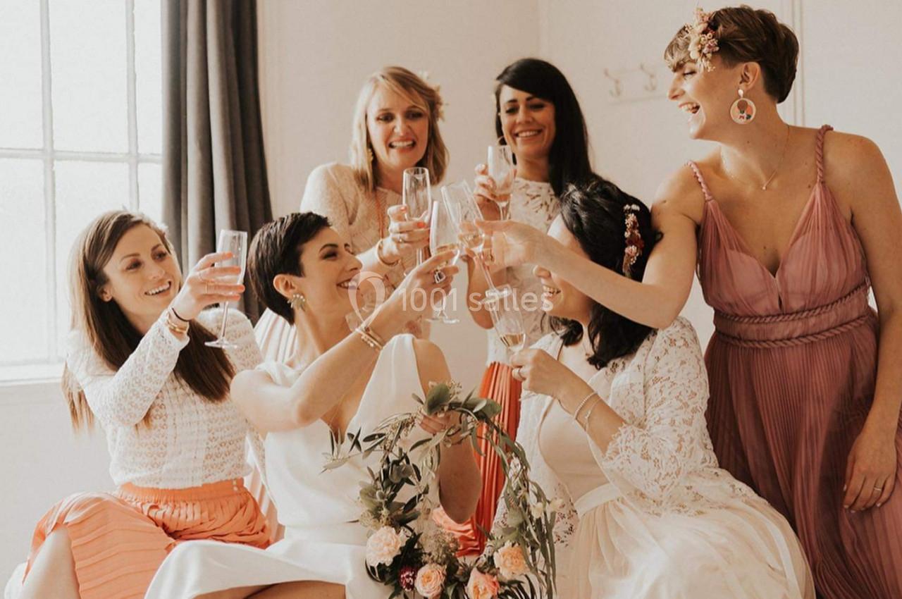 Un groupe de femmes souriantes trinquent avec des verres de champagne dans une pièce lumineuse.