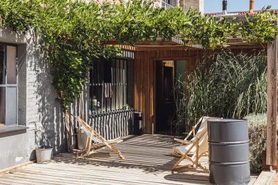Salle lumineuse avec de grandes tables en bois dressées, chaises noires, décor minimaliste et verrière en hauteur.