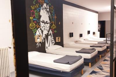 Salle lumineuse avec de grandes tables en bois dressées, chaises noires, décor minimaliste et verrière en hauteur.