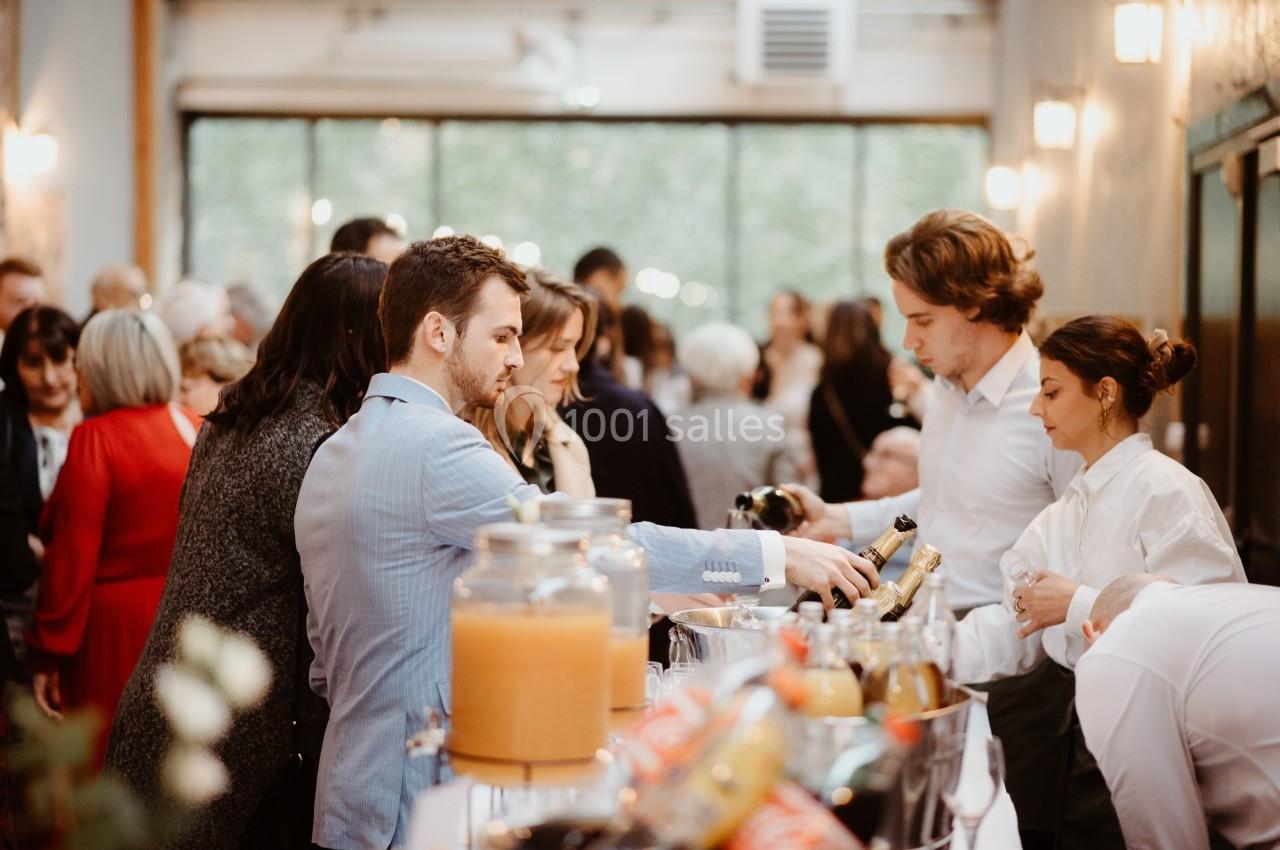 Des personnes se servent à un buffet dans un espace lumineux avec de grandes fenêtres et une ambiance conviviale.