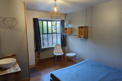 Salle lumineuse avec de grandes tables en bois dressées, chaises noires, décor minimaliste et verrière en hauteur.