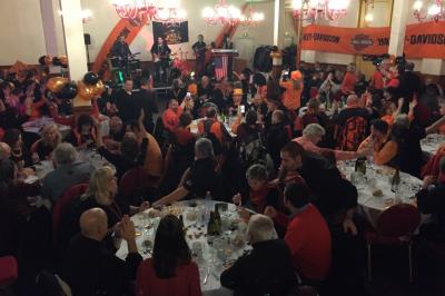 Salle sombre avec un public debout face à une scène éclairée où des musiciens jouent sous des projecteurs colorés.