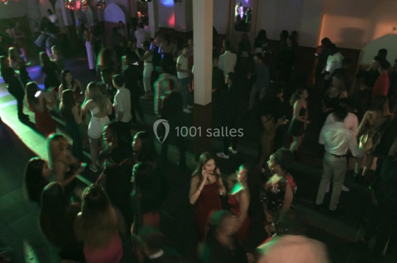 Groupe de personnes dans une salle sombre, éclairée par des lumières colorées, lors d'un événement festif.
