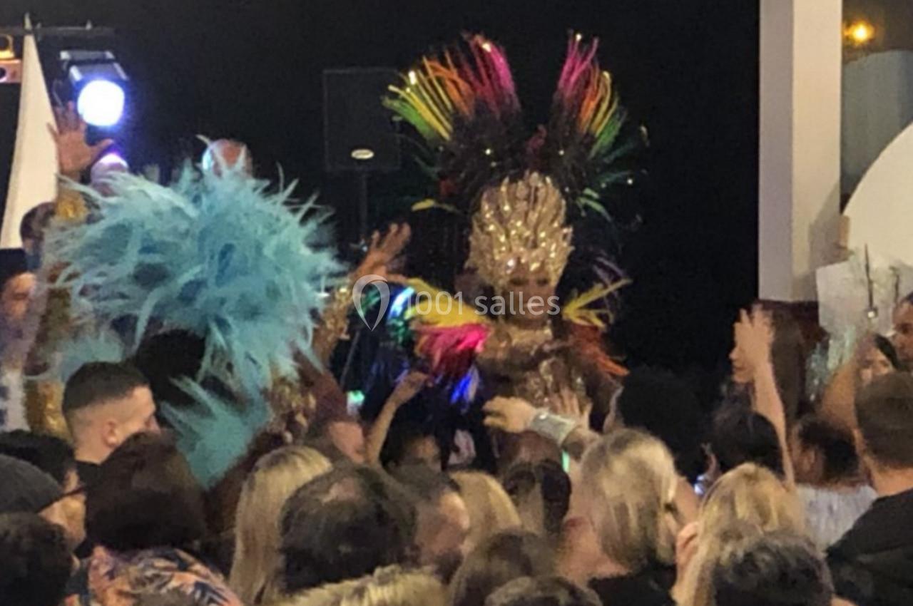 Personne en costume coloré avec coiffe à plumes au milieu d'une foule dans une ambiance festive.
