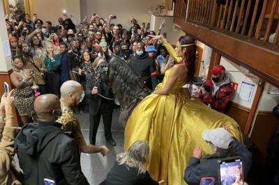 Salle sombre avec un public debout face à une scène éclairée où des musiciens jouent sous des projecteurs colorés.