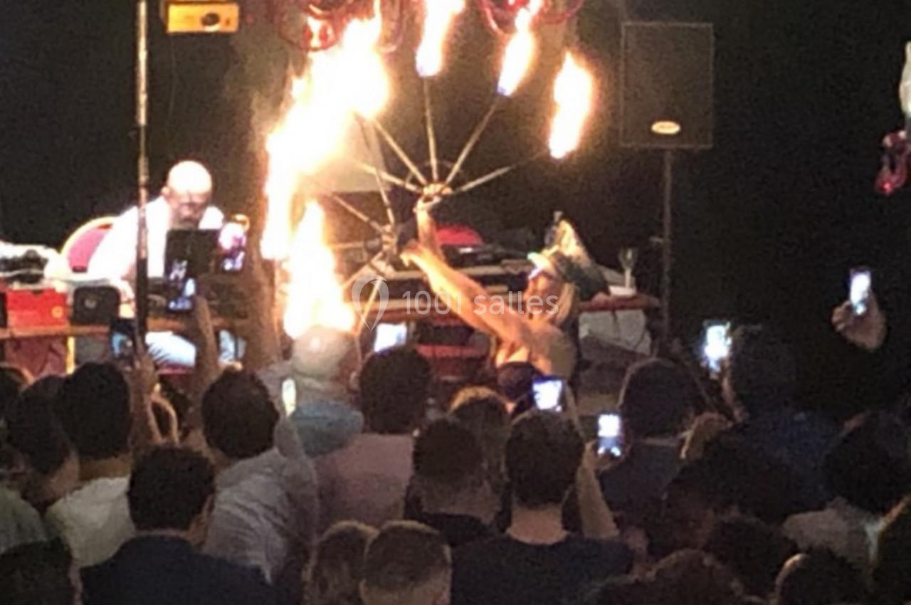 Un artiste manipule des flammes devant un public rassemblé, dans une ambiance de spectacle nocturne.