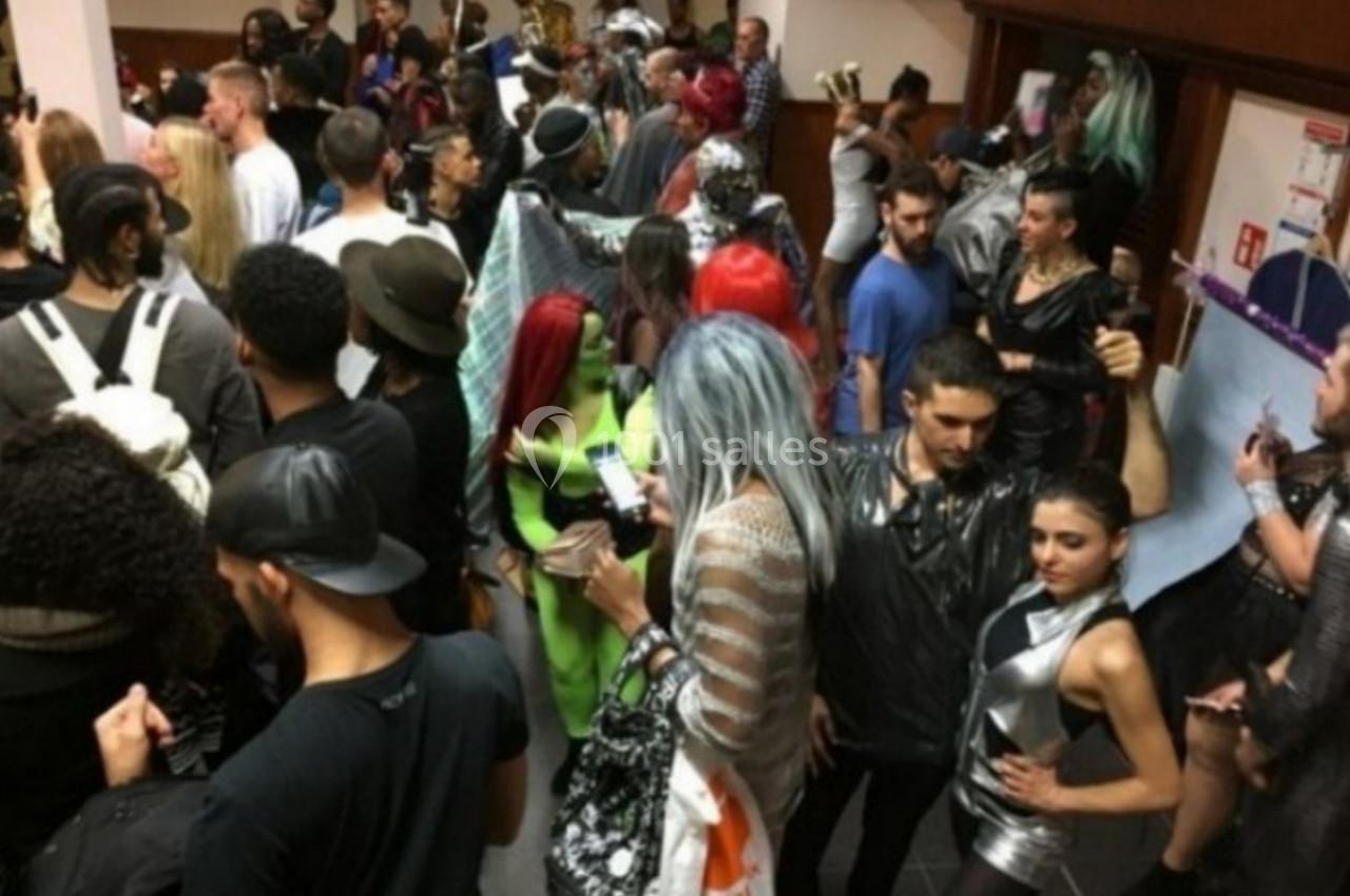 Groupe de personnes en tenues variées lors d'un événement intérieur animé.