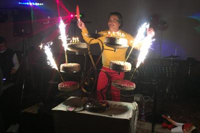 Salle sombre avec un public debout face à une scène éclairée où des musiciens jouent sous des projecteurs colorés.