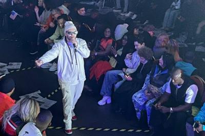 Salle sombre avec un public debout face à une scène éclairée où des musiciens jouent sous des projecteurs colorés.