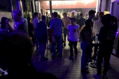 Salle sombre avec un public debout face à une scène éclairée où des musiciens jouent sous des projecteurs colorés.