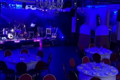 Salle sombre avec un public debout face à une scène éclairée où des musiciens jouent sous des projecteurs colorés.