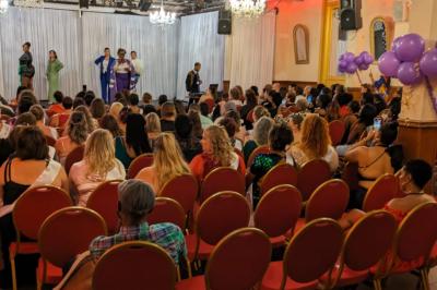 Salle sombre avec un public debout face à une scène éclairée où des musiciens jouent sous des projecteurs colorés.