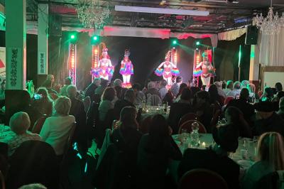 Salle sombre avec un public debout face à une scène éclairée où des musiciens jouent sous des projecteurs colorés.