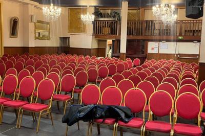 Salle sombre avec un public debout face à une scène éclairée où des musiciens jouent sous des projecteurs colorés.