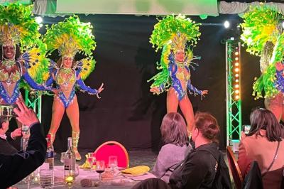 Salle sombre avec un public debout face à une scène éclairée où des musiciens jouent sous des projecteurs colorés.