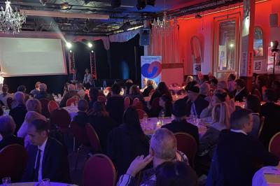 Salle sombre avec un public debout face à une scène éclairée où des musiciens jouent sous des projecteurs colorés.