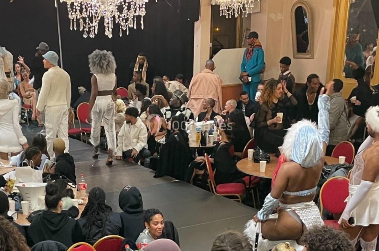 Des personnes assistent à un événement festif en intérieur, avec des participants en tenues créatives et des chandeliers…