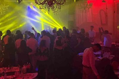 Salle sombre avec un public debout face à une scène éclairée où des musiciens jouent sous des projecteurs colorés.