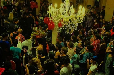 Salle sombre avec un public debout face à une scène éclairée où des musiciens jouent sous des projecteurs colorés.